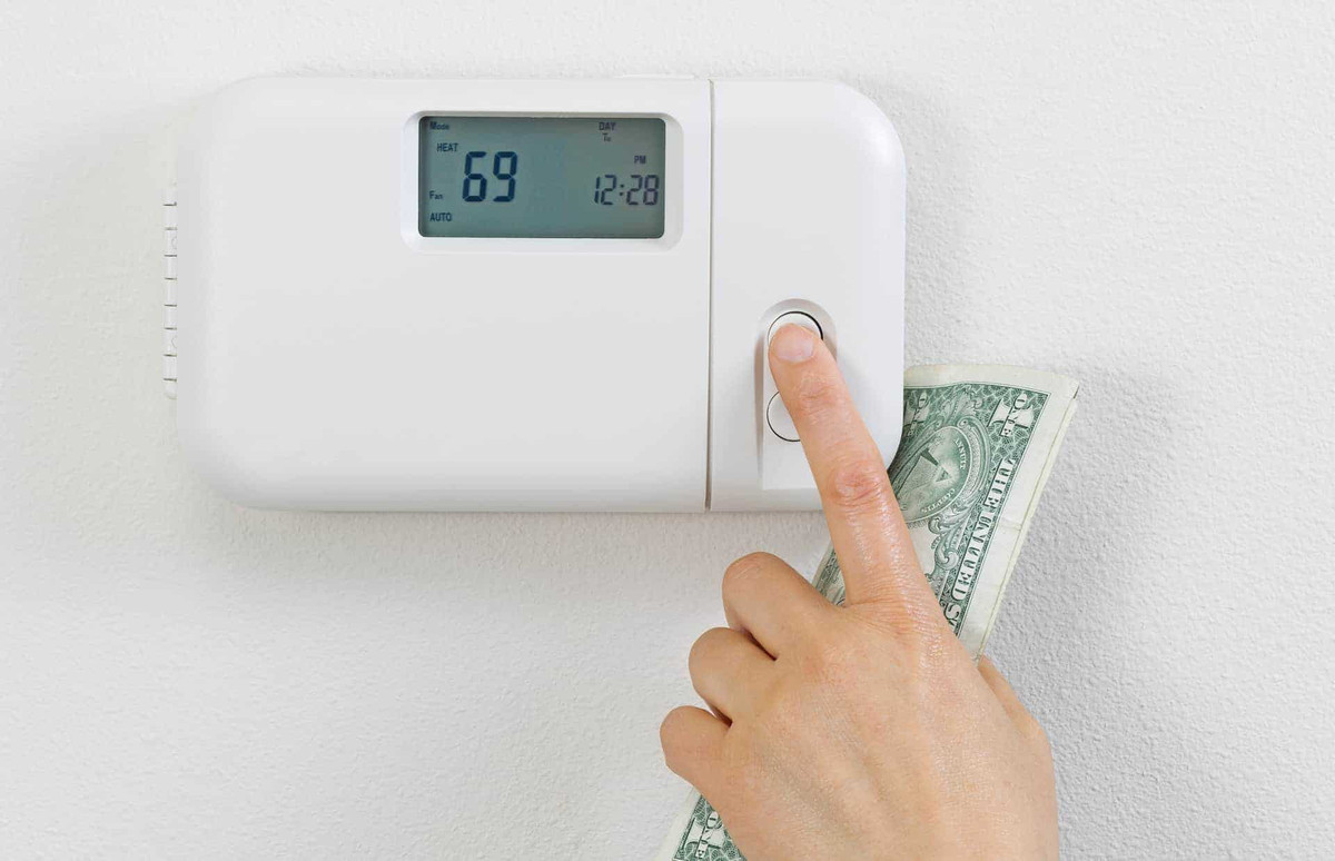 A hand changing the temperature on the thermostat.