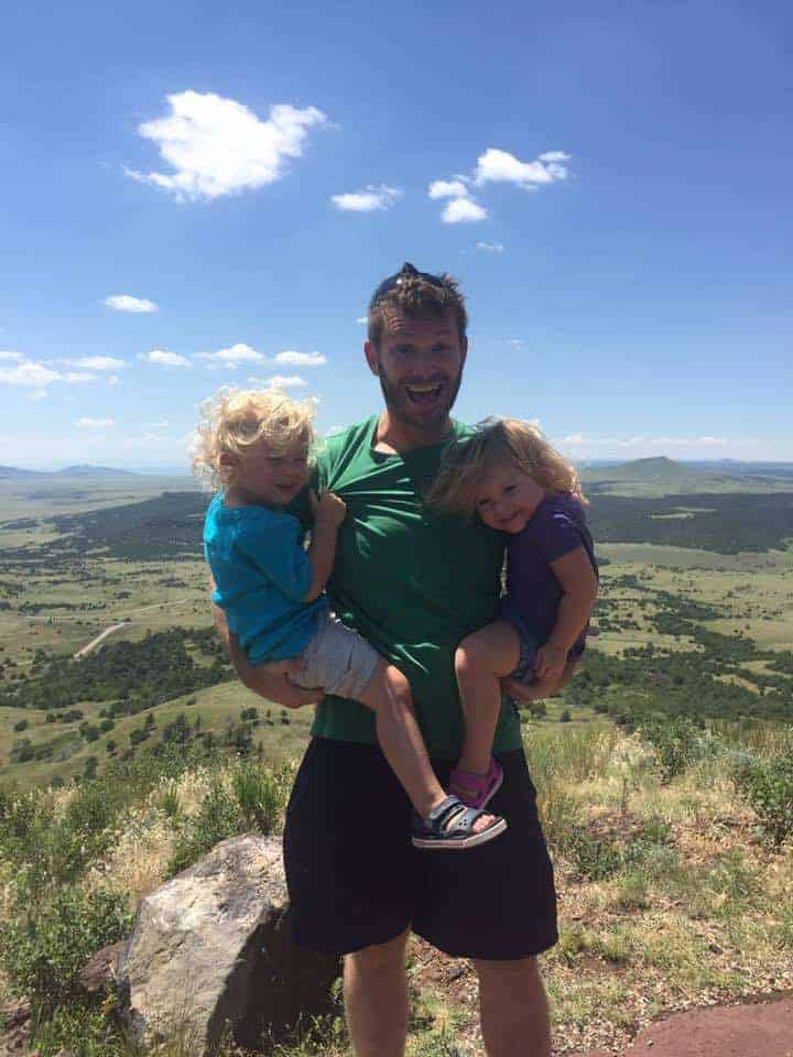 Justin Houck holding two children with a valley down below and behind them