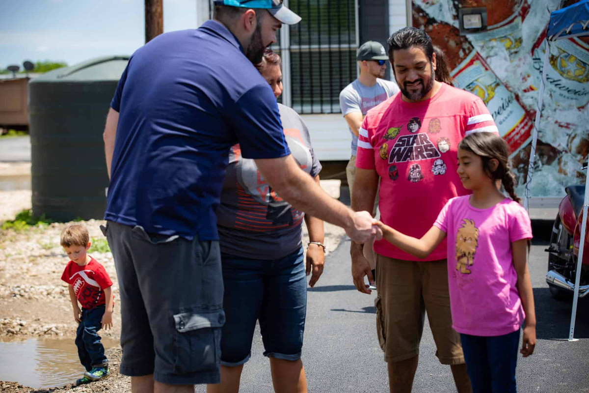 Alberto Piña shaking a girl's hand next to her parents at the Braustin Homes 2019 Dealership grand opening party