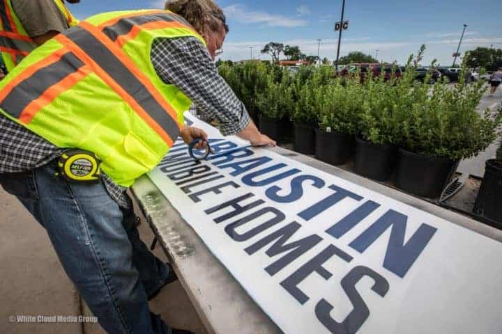 Worker setting up a Braustin sign to be mounted on a building