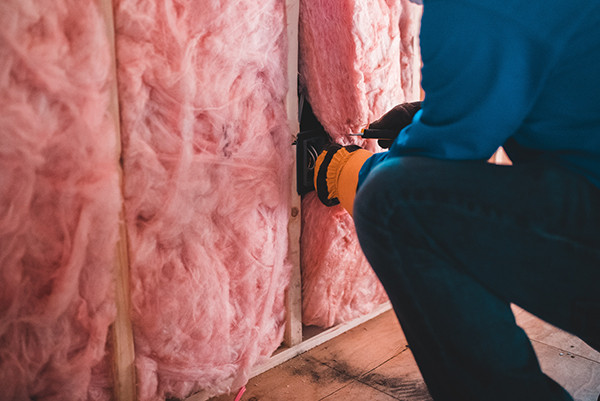 man making mobile home more energy-efficient by adding new insulation.